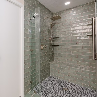 Walk-in shower with small mosaic floor tiles that provide additional traction for safer aging-in-place bathroom design.