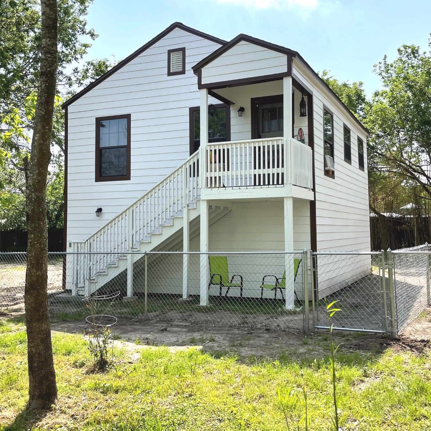 Restored guest house exterior with white siding, dark trim, and a rebuilt staircase and elevated porch
