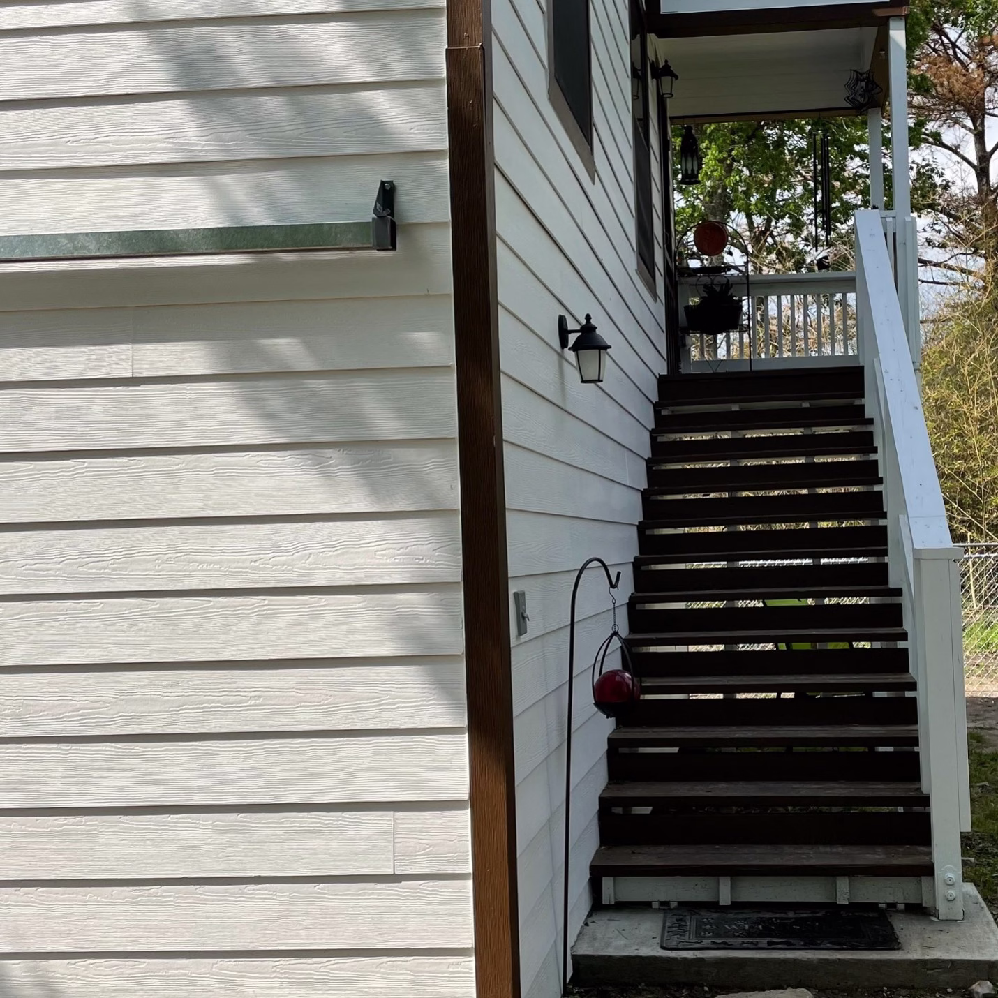 Rebuilt exterior staircase with dark wood treads and white railings leading to the renovated guest house entrance