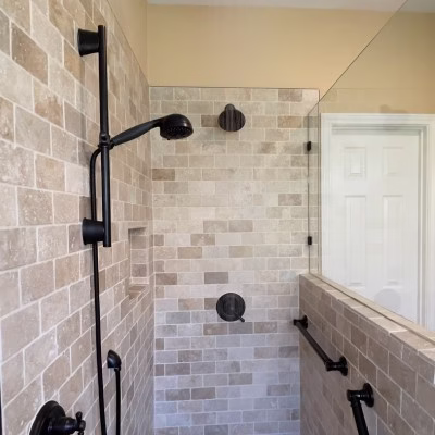 Accessible walk-in shower with a handheld shower head, grab bars, and adjustable slide bar for aging-in-place bathroom design.