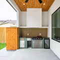Covered outdoor kitchen with built-in grill, sink, mini refrigerator, and green cabinetry.