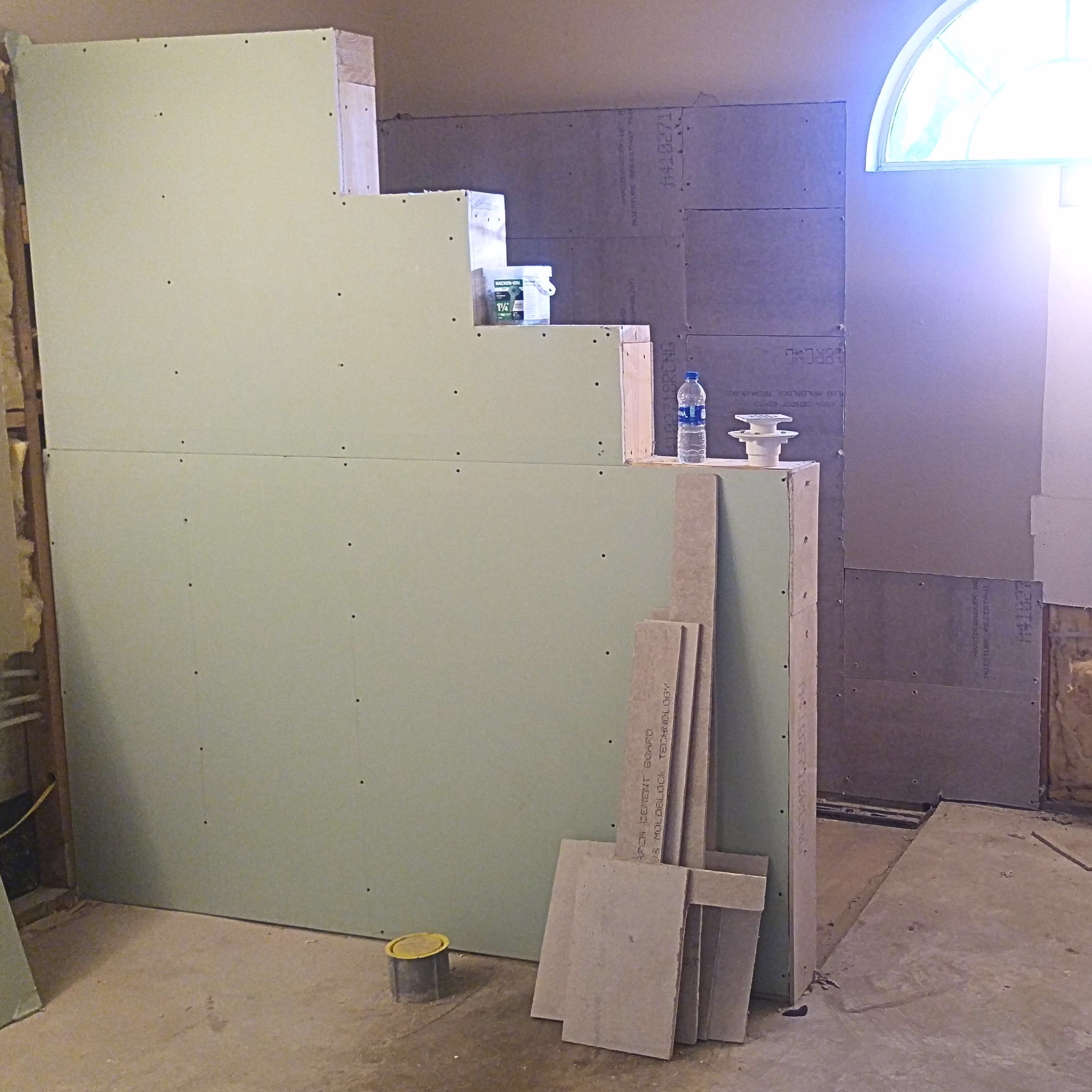 Bathroom remodel in progress with exposed wall framing, tile backer board, and shower walls being prepared for tile installation.