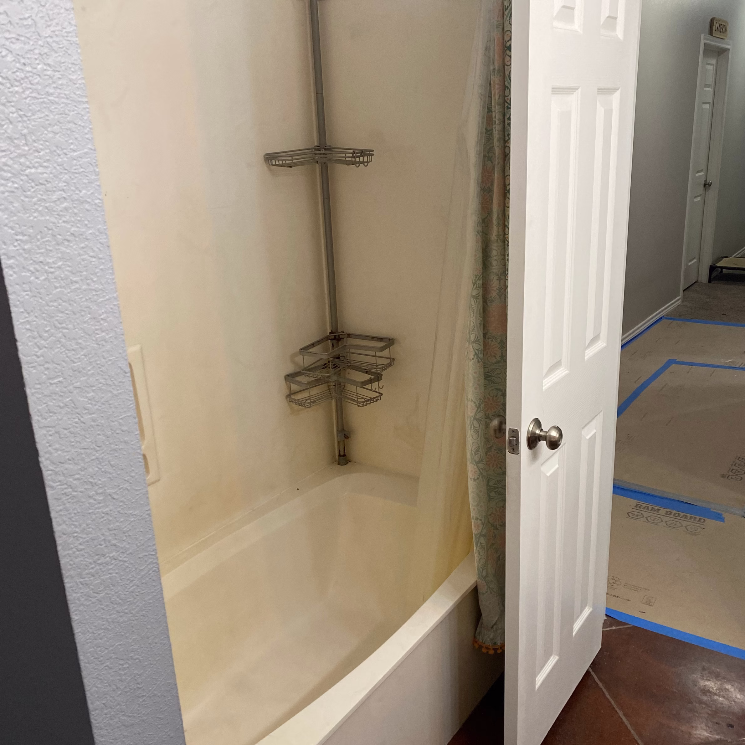 Existing guest bathroom tub and shower combination with molded surround and shower curtain before remodeling.