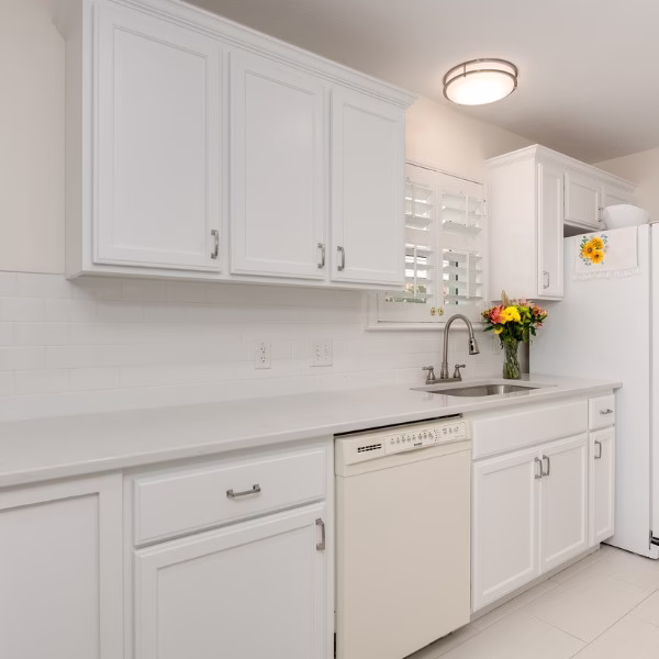 Kitchen remodel with painted white cabinets, quartz countertops, stainless steel sink, and classic subway tile backsplash.