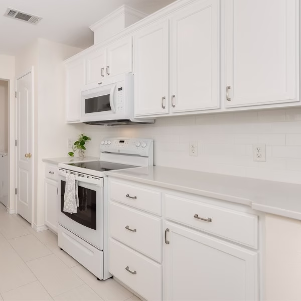 Remodeled kitchen featuring painted cabinets, white quartz countertops, subway tile backsplash, and updated appliances.