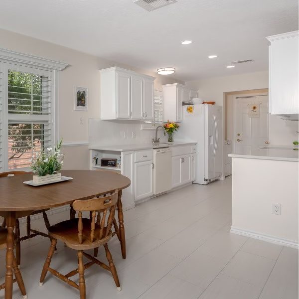 Bright remodeled kitchen with painted white cabinets, quartz countertops, updated flooring, and dining area.