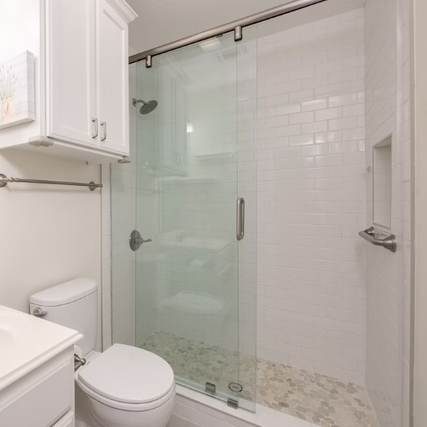 Guest bathroom remodel with walk-in shower, sliding glass enclosure, subway tile walls, and pebble shower floor.