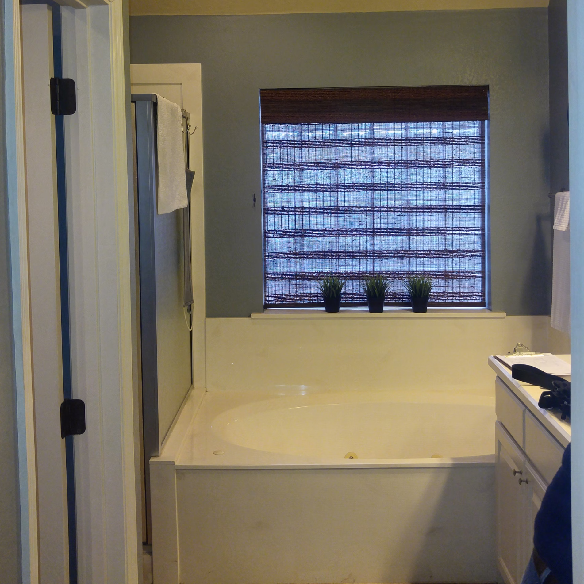 Primary bathroom before remodeling with a large jetted tub beneath the window beside the original enclosed shower.