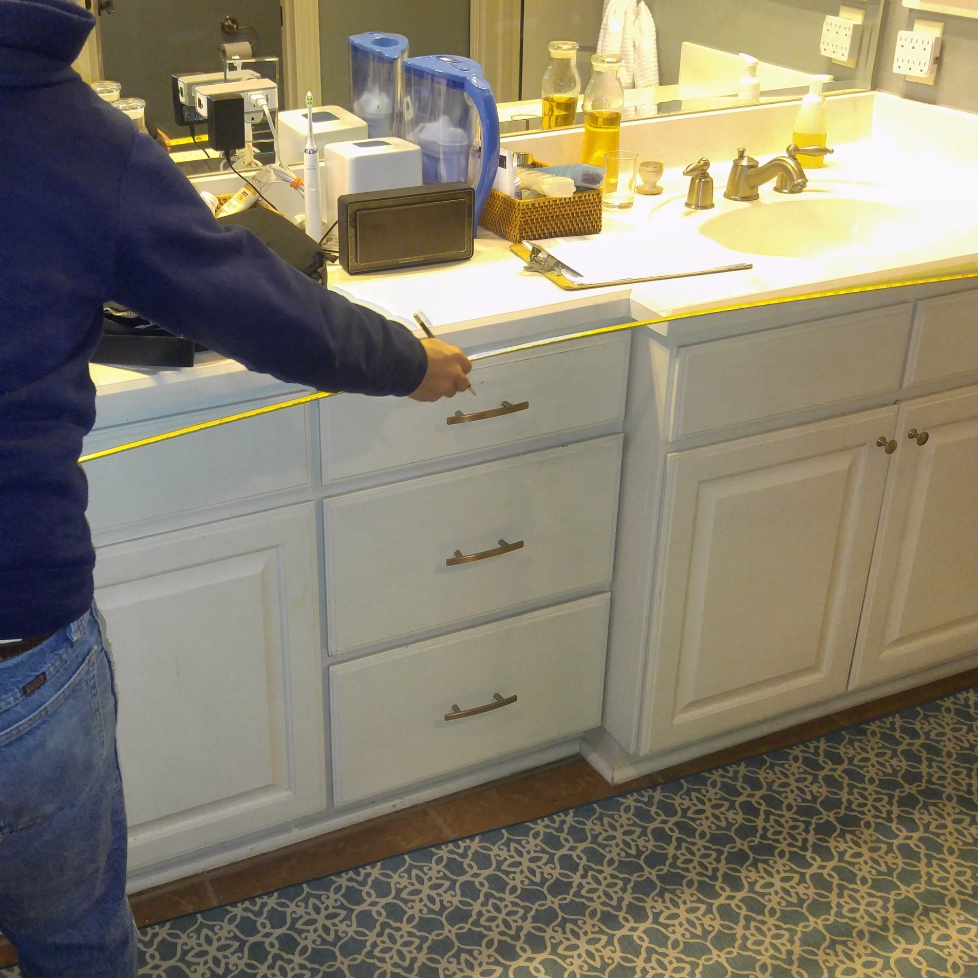 Original double vanity with white cabinetry, white countertop, large wall mirror, and bathroom items on the counter.
