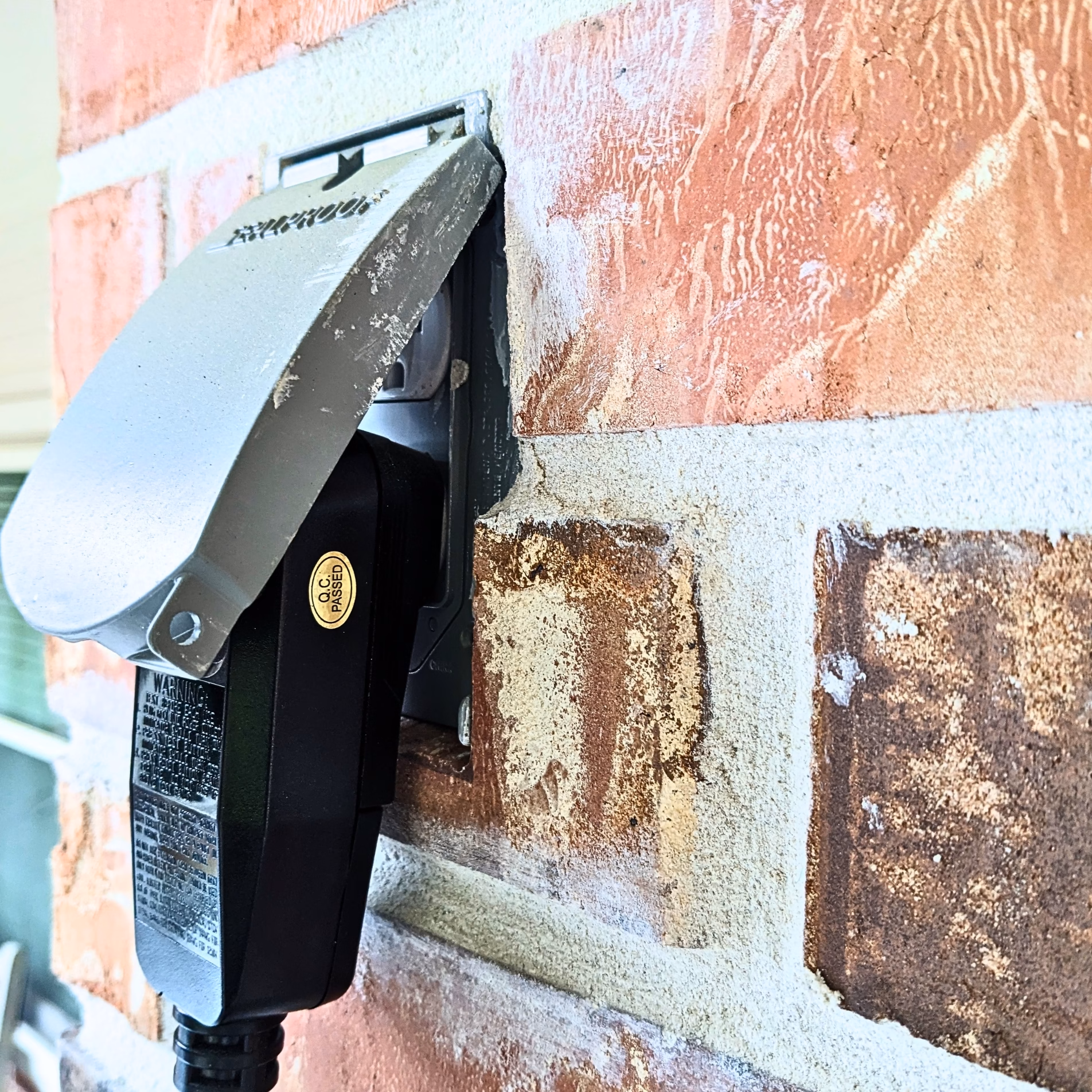 Weatherproof outdoor electrical outlet mounted on a brick column of the covered patio addition in College Station.