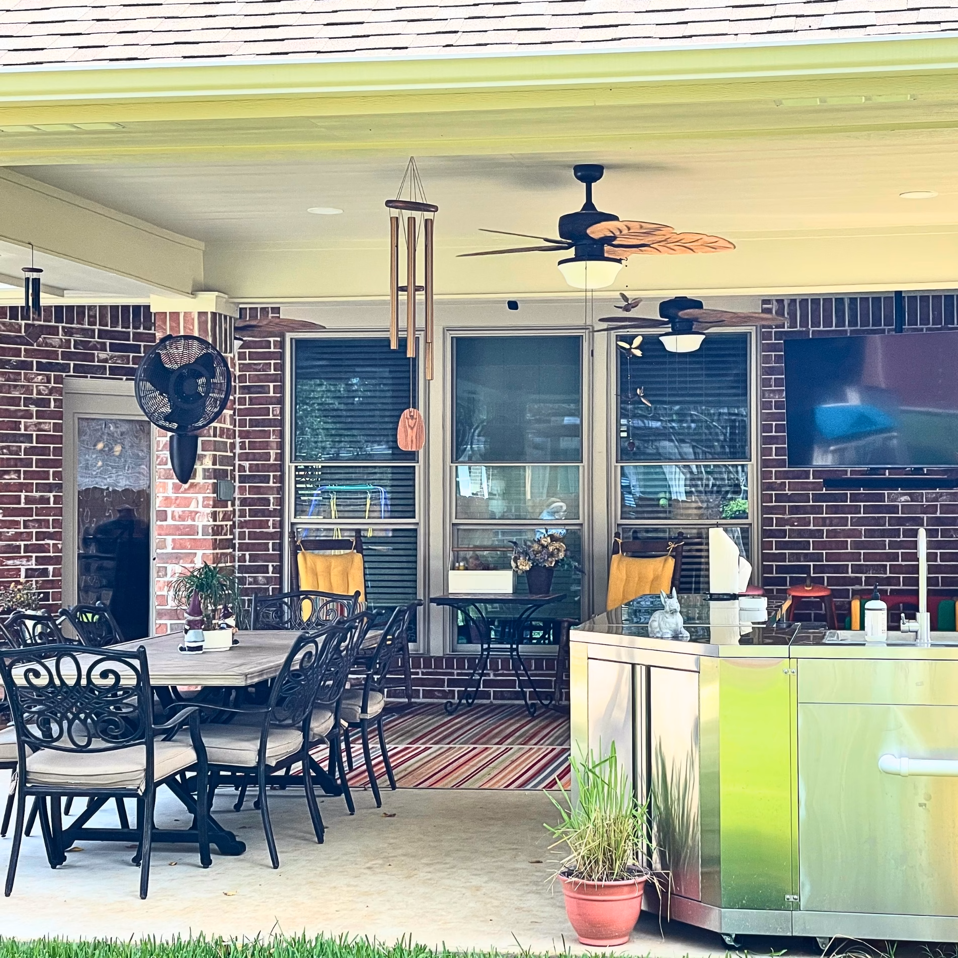 Completed covered patio addition featuring outdoor dining furniture, ceiling fans, recessed lighting, and a stainless steel outdoor cooking station.