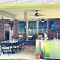 Completed covered patio addition featuring outdoor dining furniture, ceiling fans, recessed lighting, and a stainless steel outdoor cooking station.