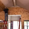 Carpenter installing natural wood wall planks during the construction phase of a home remodel.